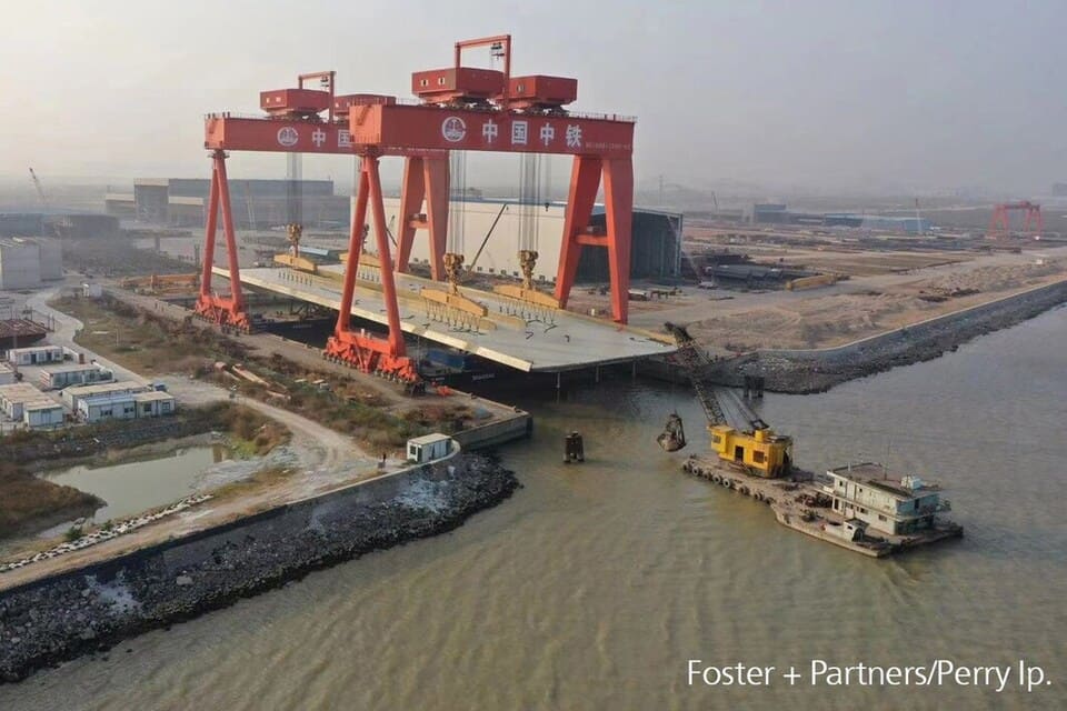 Kranar lyfter den 3 500 ton tunga Slussenbron upp på pontoner i Kina.